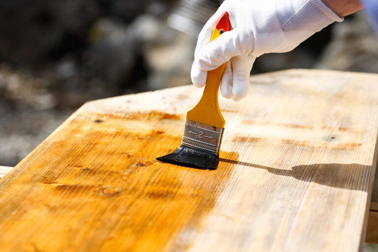 painter,holding,a,paintbrush,over,wooden,surface,,protecting,wood,for