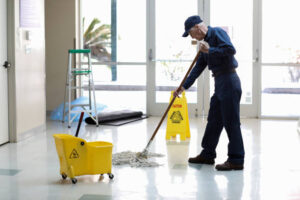 senior adult janitor keeps the floors cleaned and sanitized due to the virus.